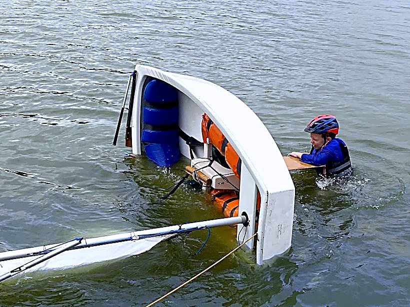 A young sailor rights a boat during a capsize drill