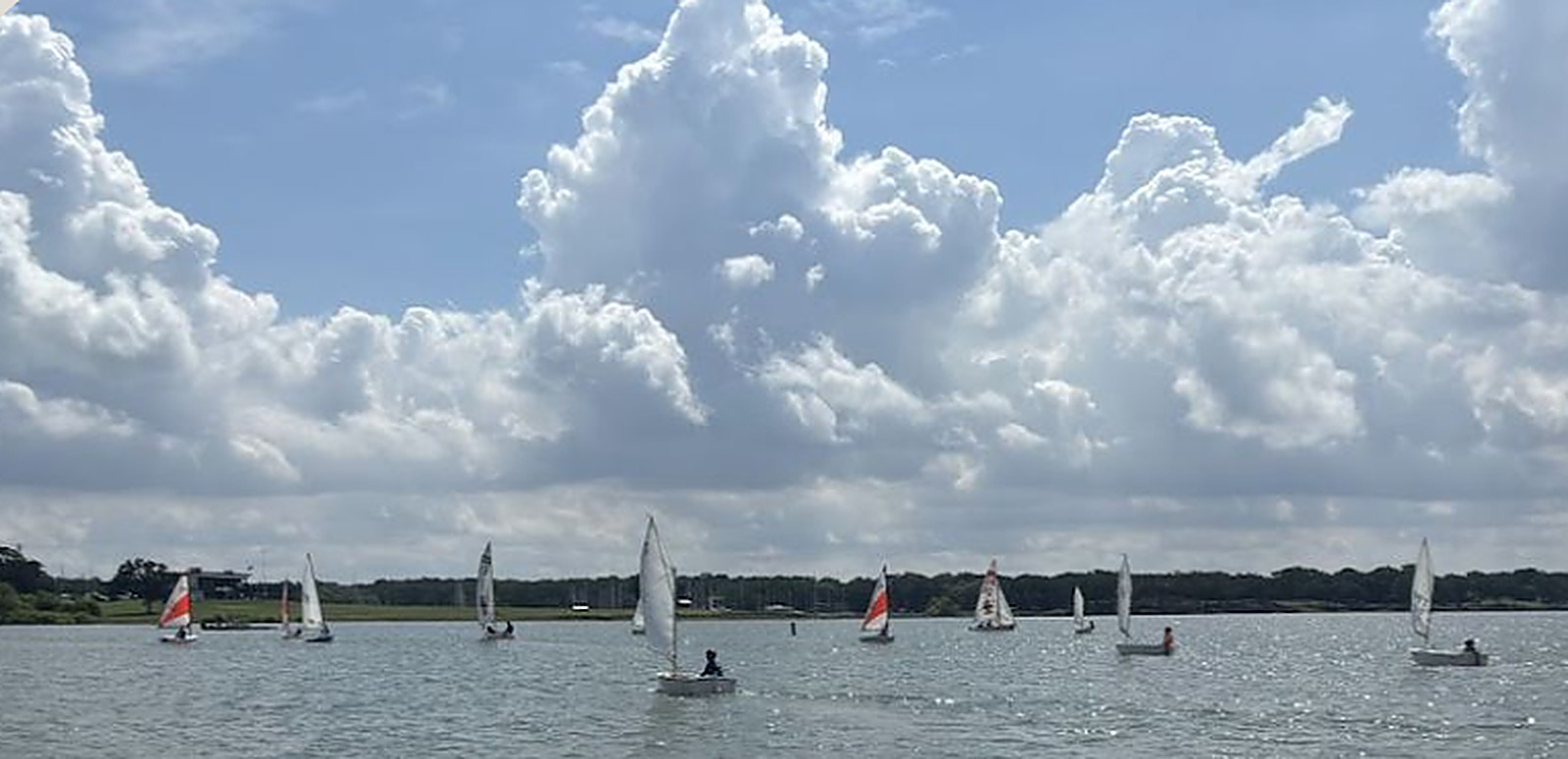 A fleet of DCYC youth dinghies scattered across Lake Lewisville under towering clouds